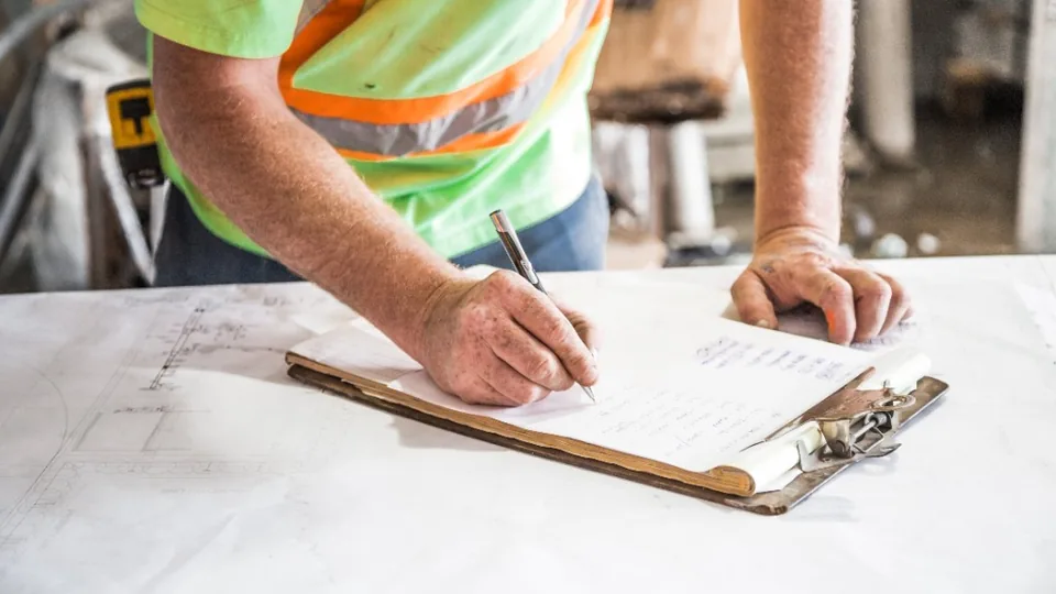 Contractor in hi-vis with clipboard on site