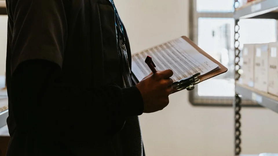 Worker recording notes on a clipboard in a warehouse